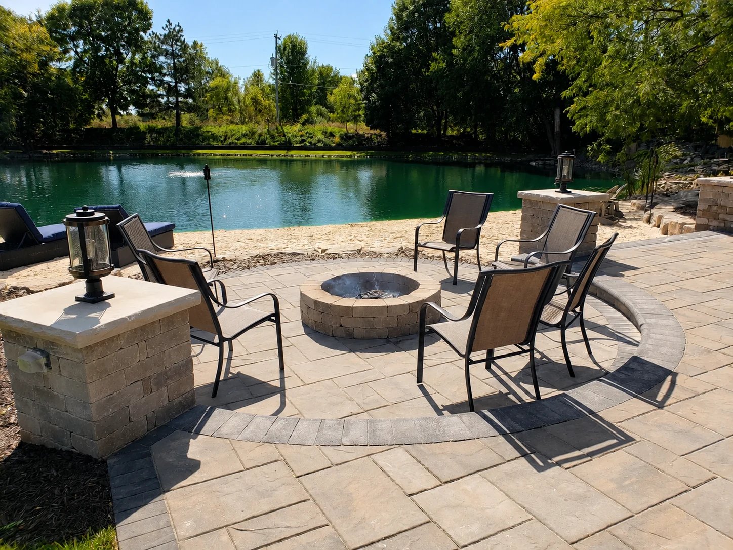 Circular firepit patio with chairs and a pond view
