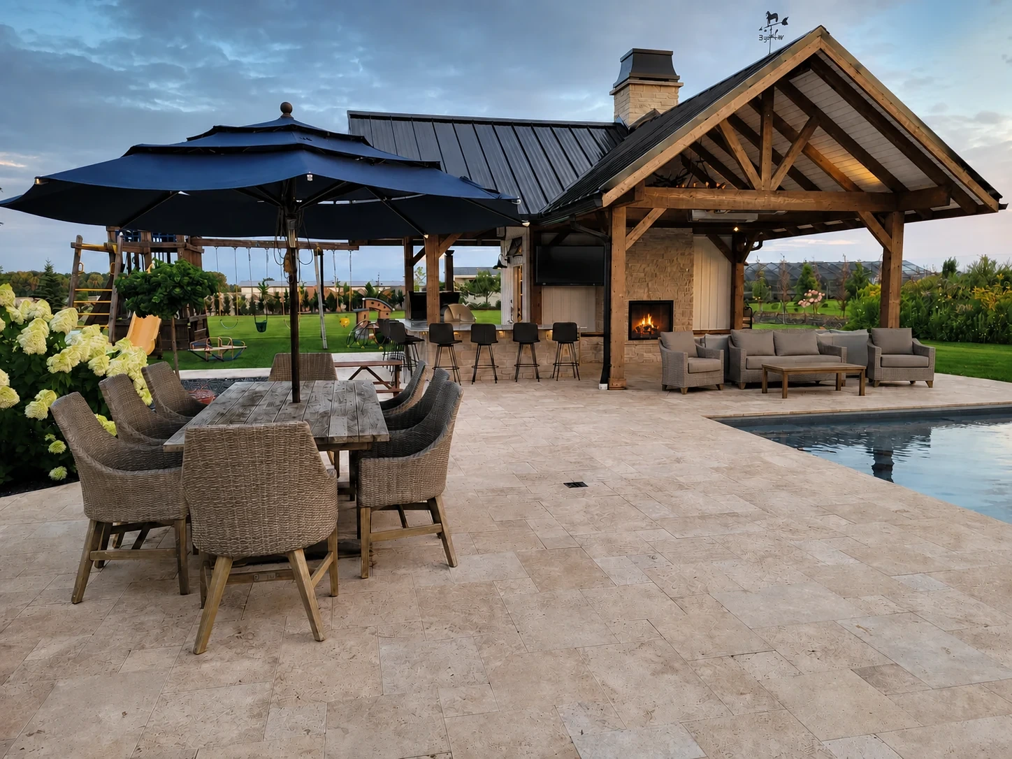 Earthscape paver patio with outdoor dining, lounge seating, a pool, and a lit stone fireplace