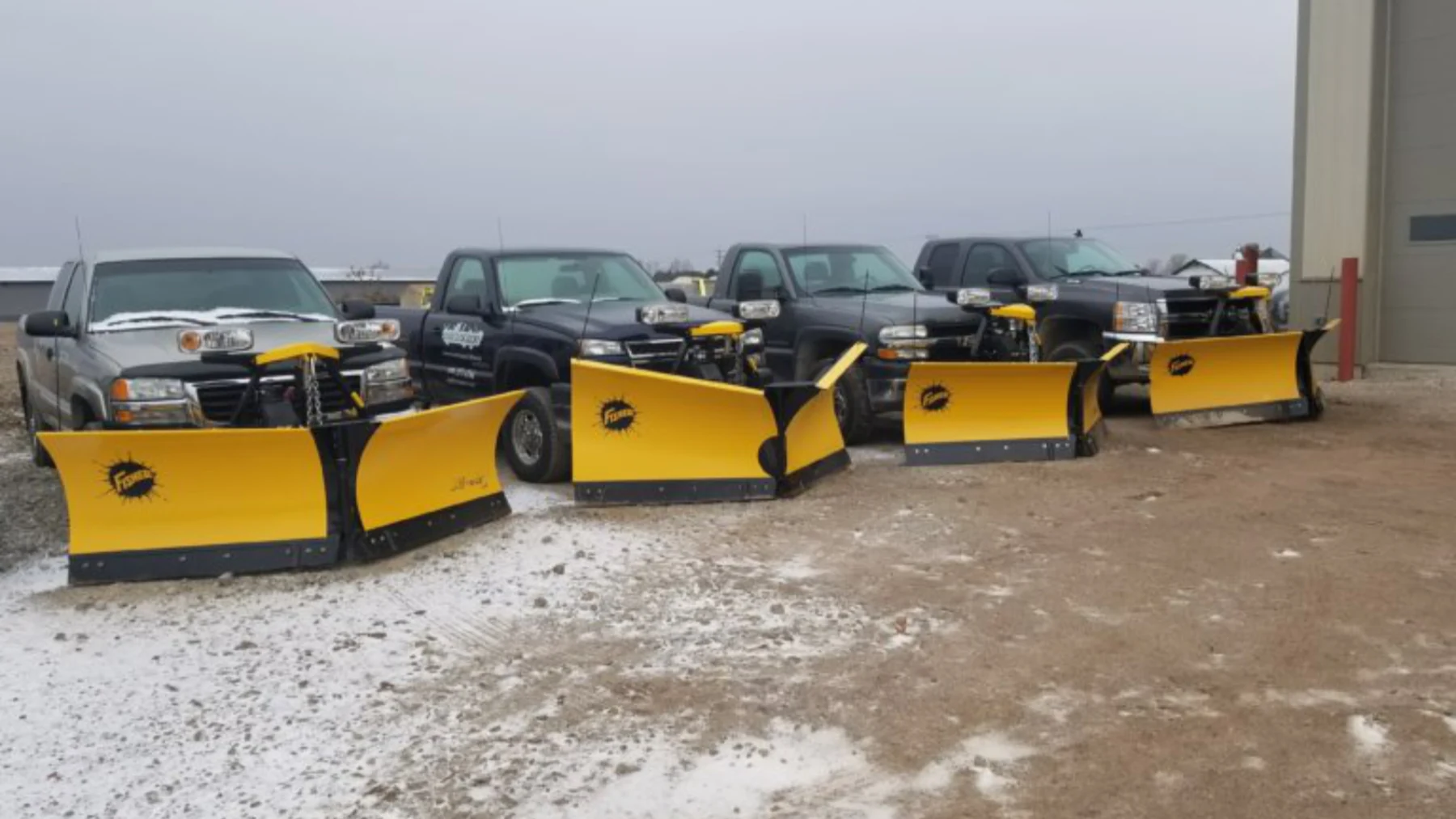 Snowplow trucks lined up with yellow blades at Earthscape