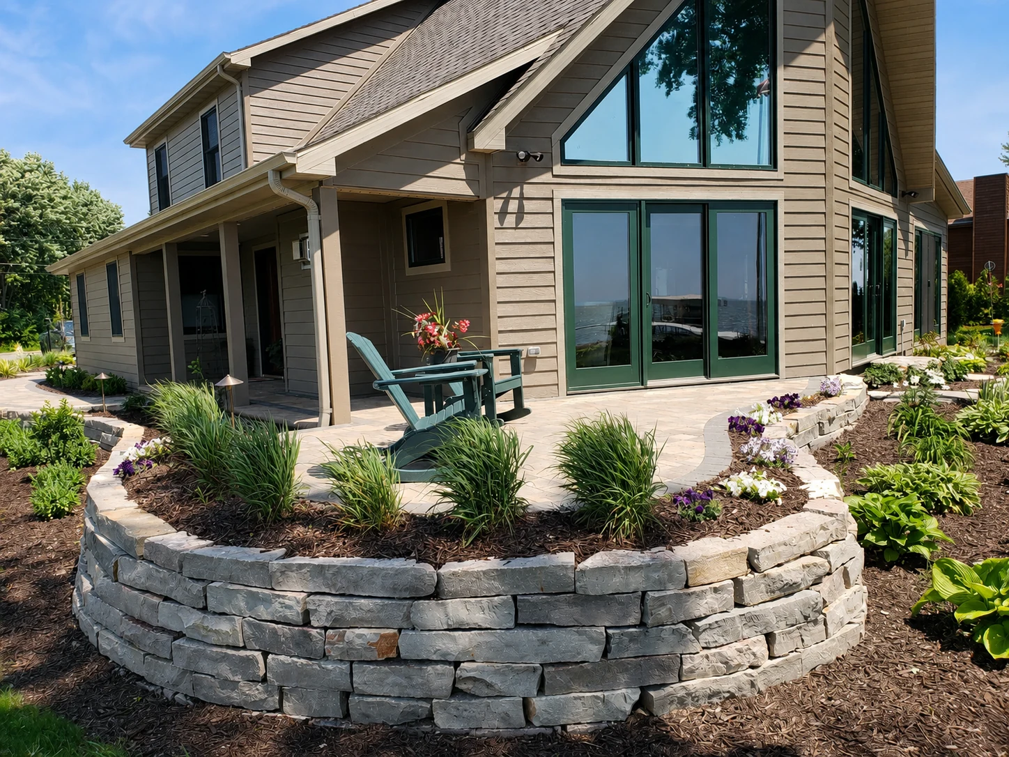 Curved stone wall with layered garden planting around a raised patio