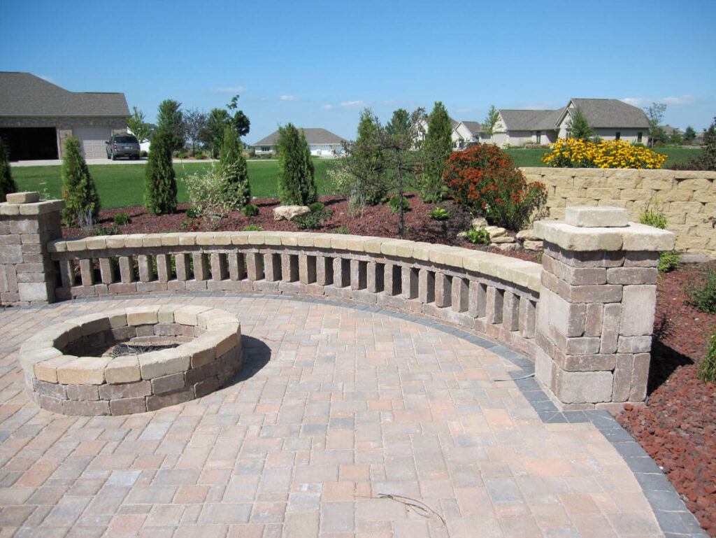 Large paver fire-pit terrace enclosed by a curved masonry wall.