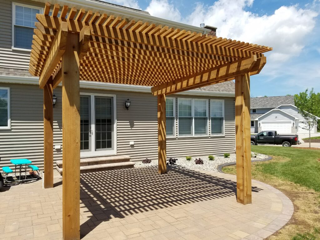 Cedar pergola casts patterned shade over a curved backyard patio.