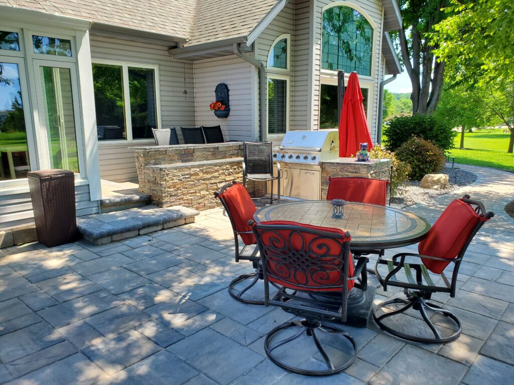 Bright red dining set on a shaded paver patio beside the home.