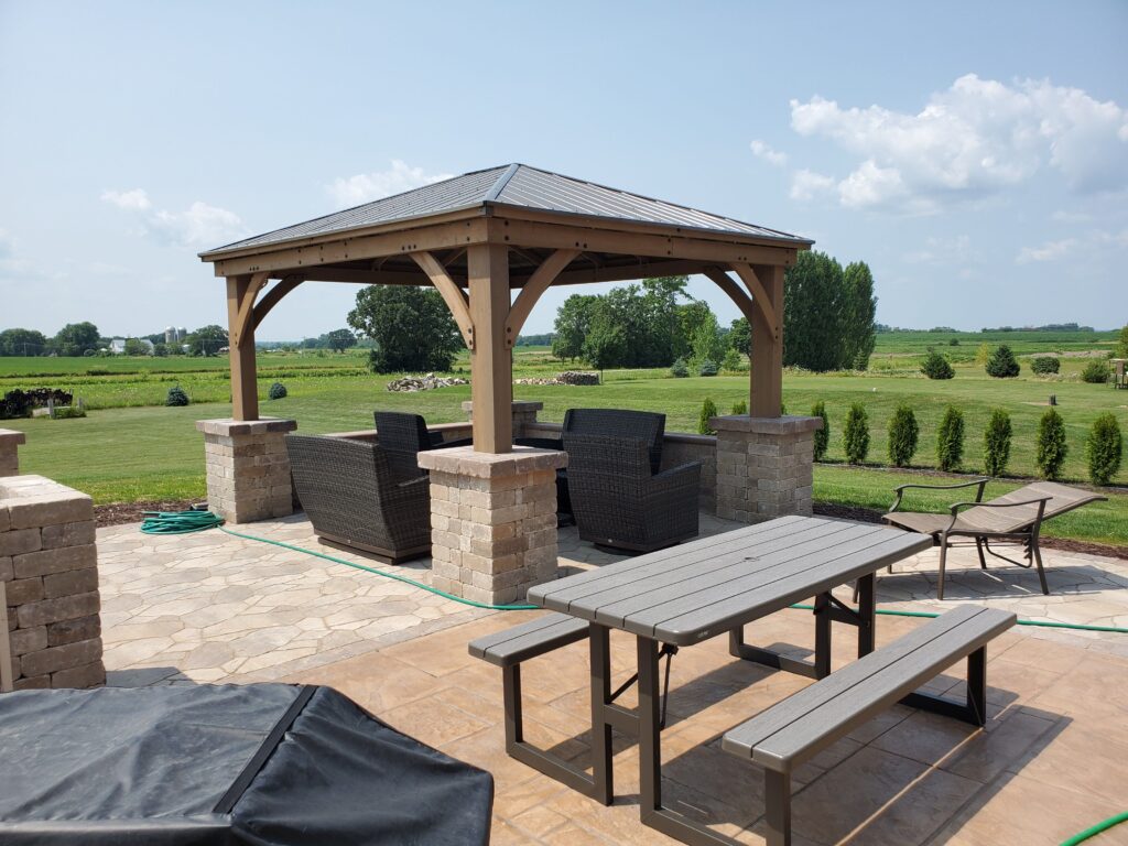 Timber pavilion with outdoor kitchen and seating on a paver patio.