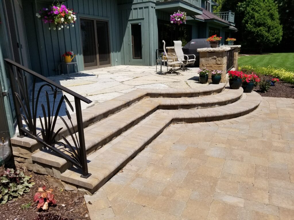 Wide curved paver steps leading from the home to a patio.