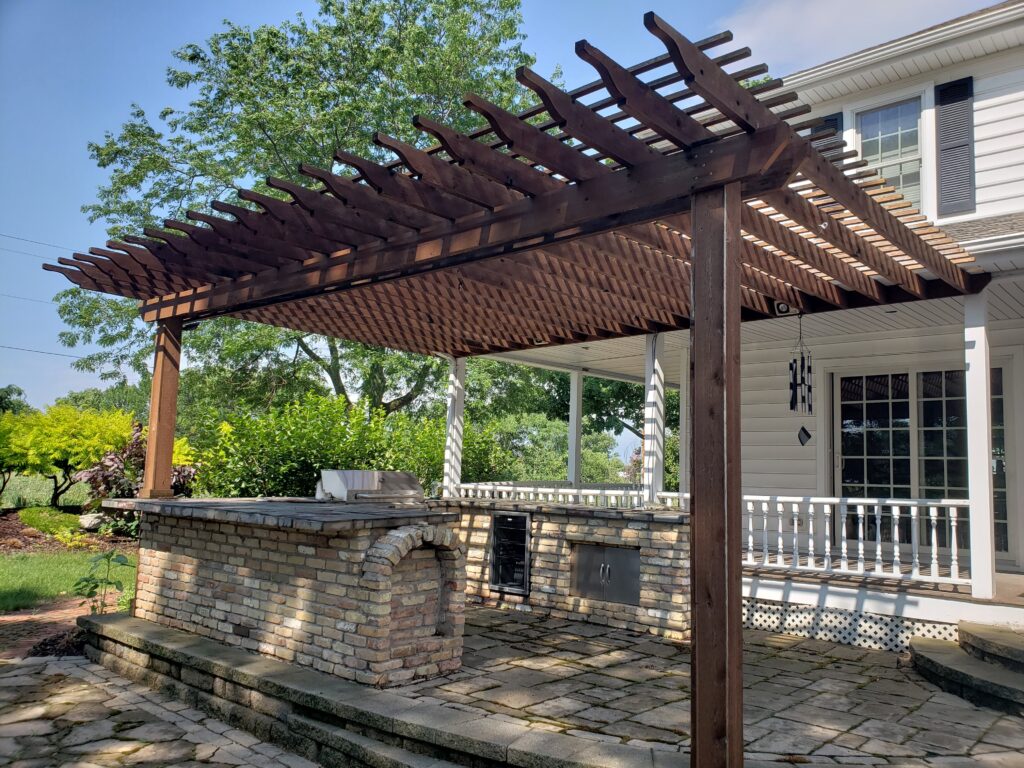 Dark cedar pergola provides shade above an elevated backyard deck.