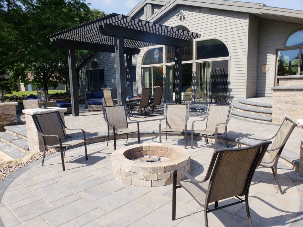 Black pergola shades seating around a circular patio fire pit.