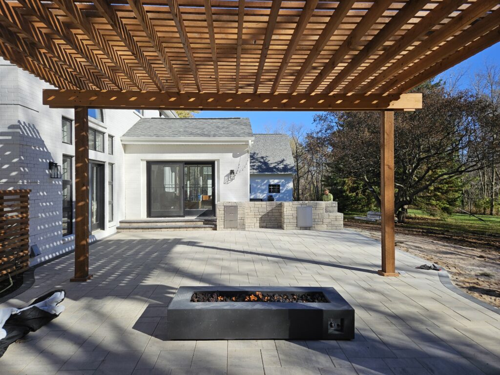 Cedar pergola shades a rectangular fire table on a modern patio.