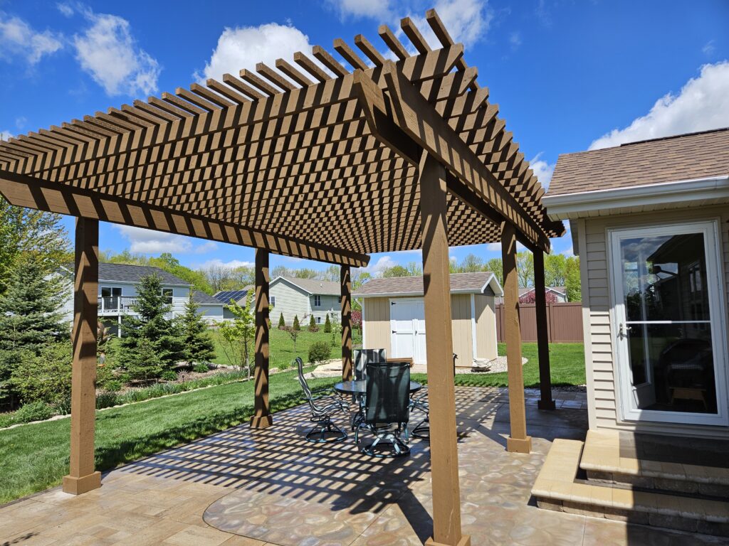 Gabled cedar pergola creates patterned shade beside the home.