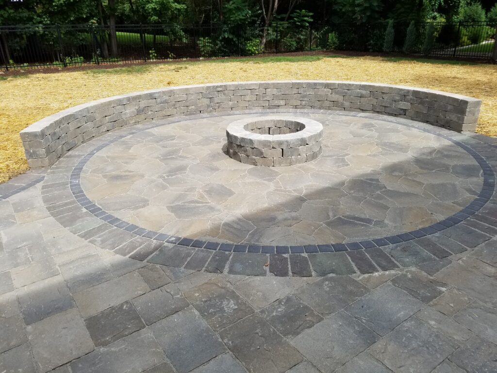 Circular fire pit centered within an inlaid multitone paver design.