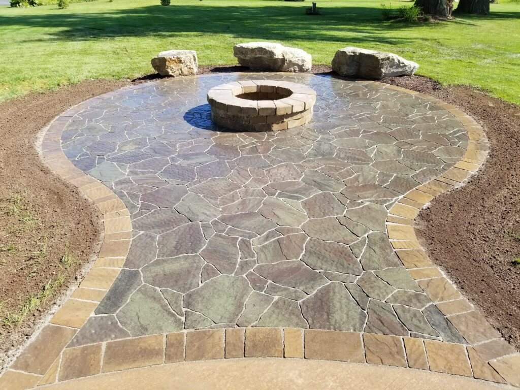 Stone fire pit and boulder seats on an organic flagstone patio.