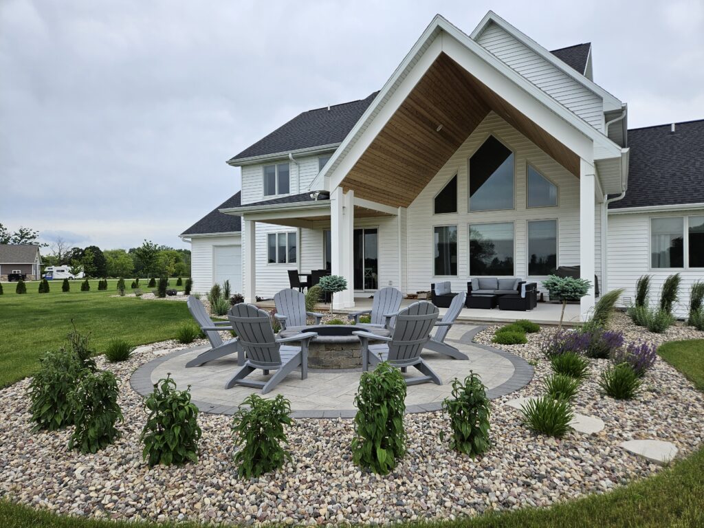 Large fire-pit terrace and lounge seating behind a modern white home.