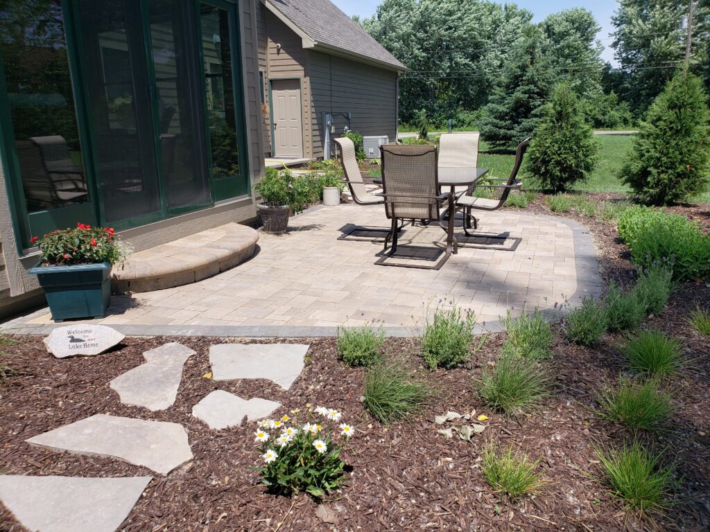 Small circular paver patio with chairs framed by landscaped beds.