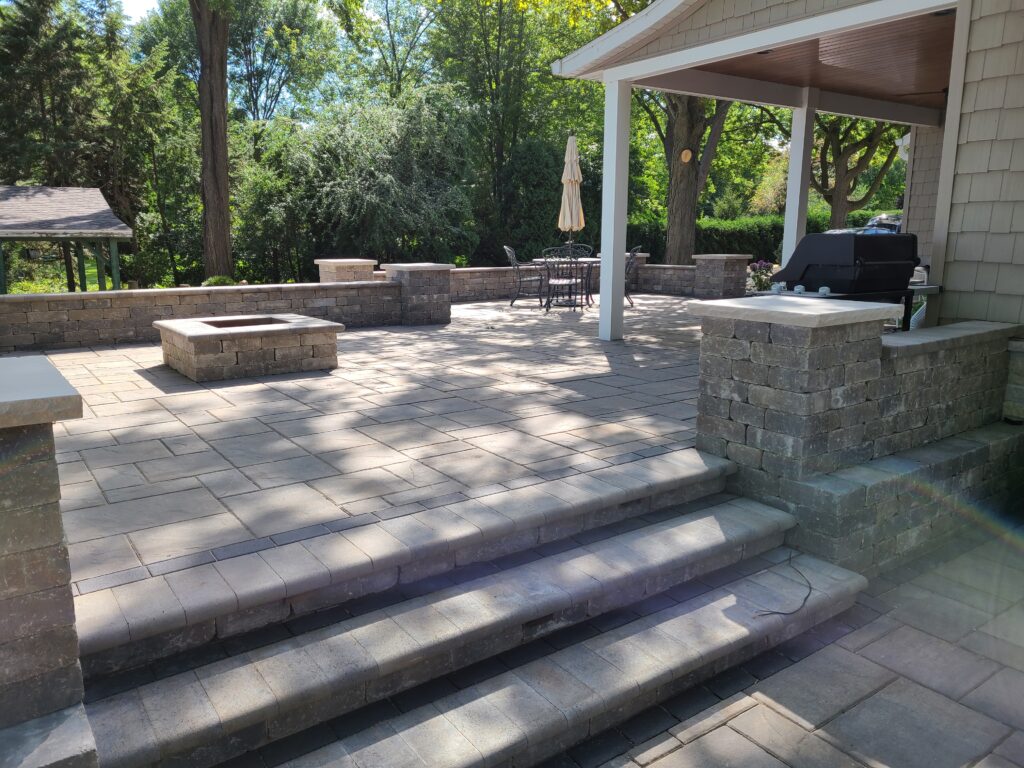 Wide paver steps lead to a covered patio with stone columns.