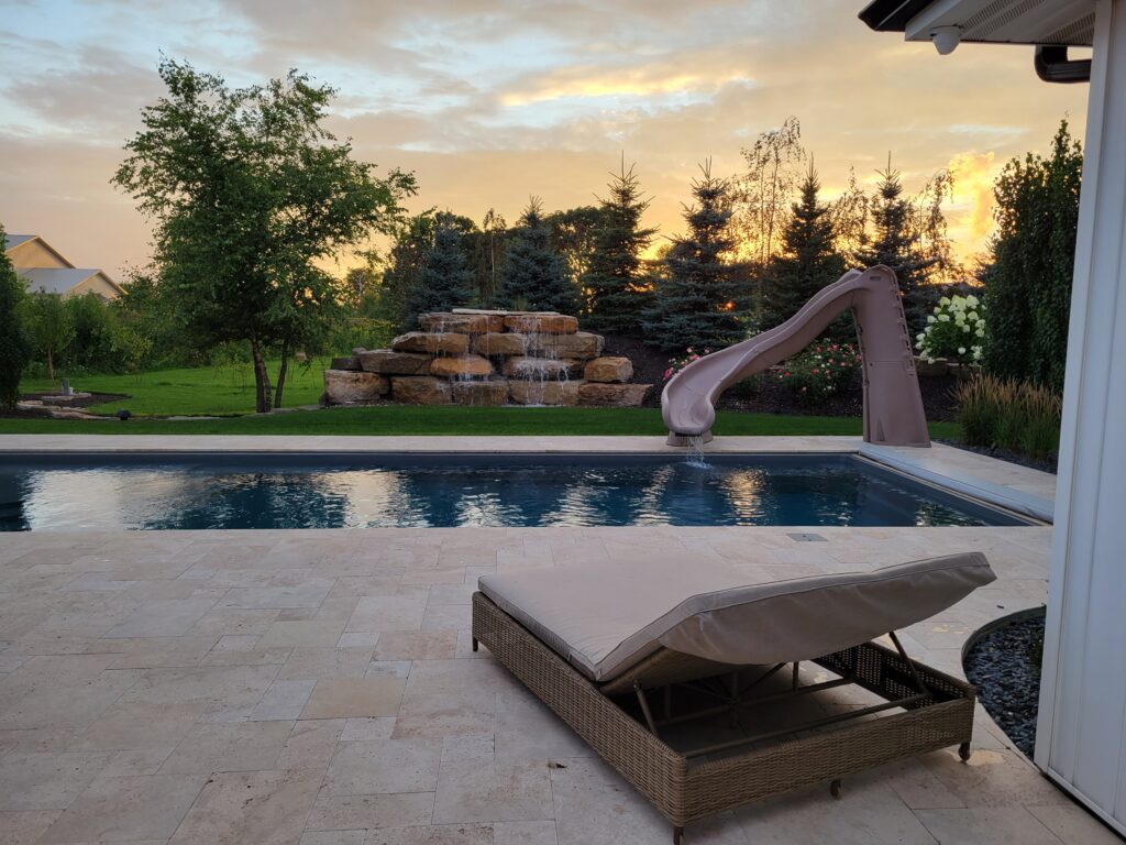Poolside paver terrace with lounge seating at sunset.
